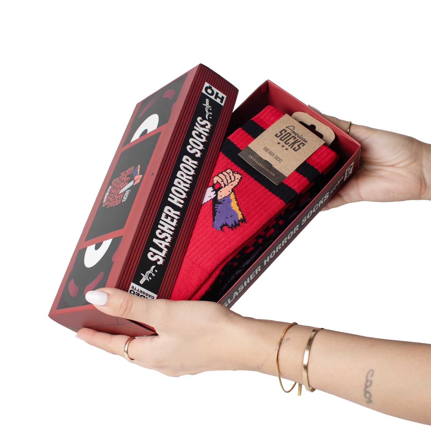 Hands opening slasher horror movie inspired gift box including iconic psycho inspired socks by american socks