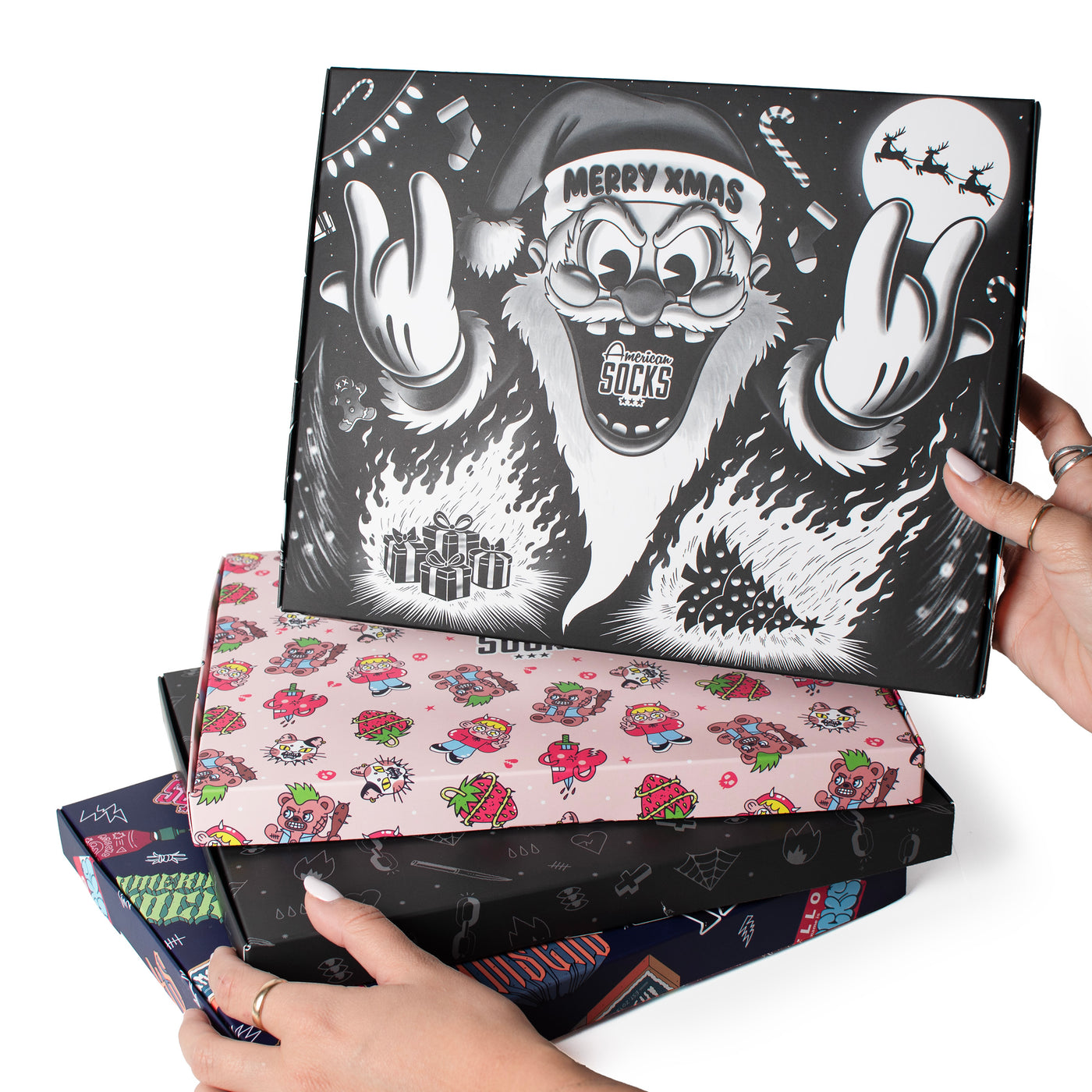 Four unique piled up gift boxes with different designs held by hands by American Socks 